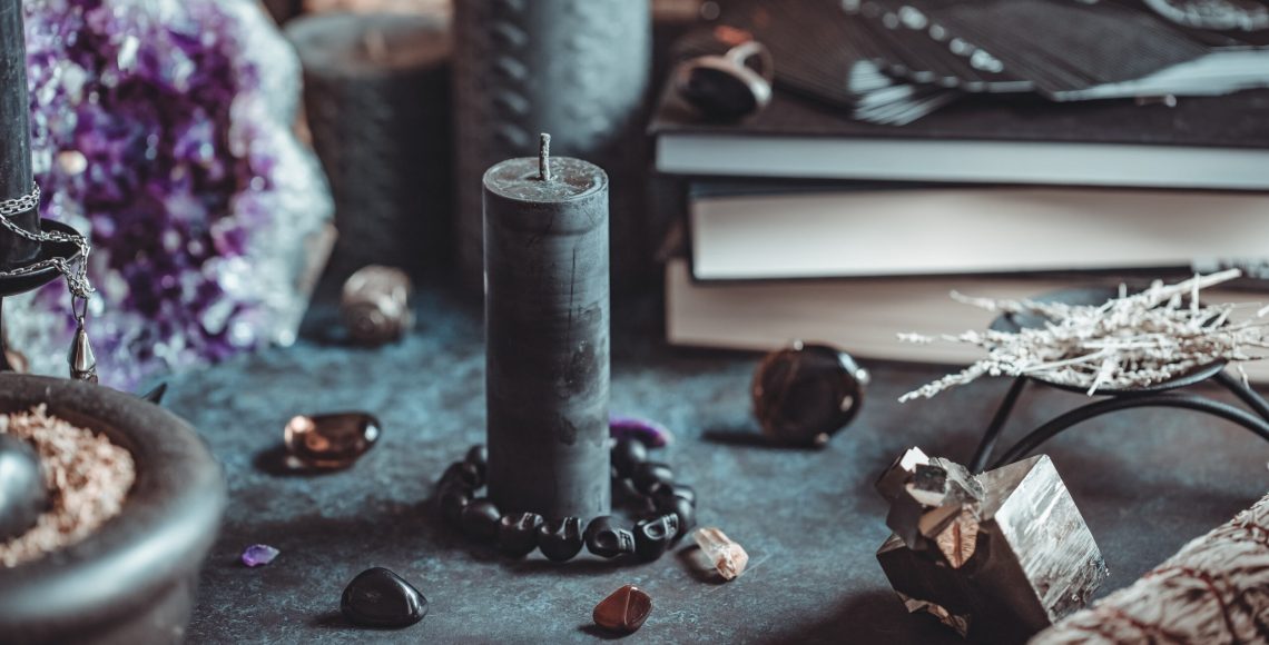 Black candle on a witch's altar for a magical ceremony among crystals and black candles.
